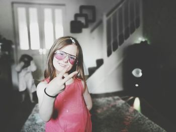 Portrait of girl wearing sunglasses standing at home