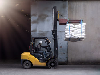 Manual worker driving forklift while working at warehouse