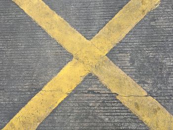 High angle view of yellow arrow sign on wood