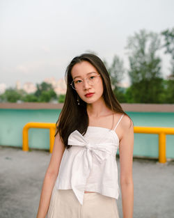 Portrait of beautiful young woman standing against white background