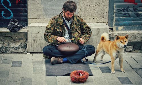 Full length of man sitting with dog