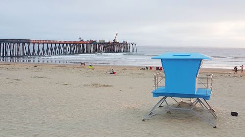 Deck chairs on beach against sky