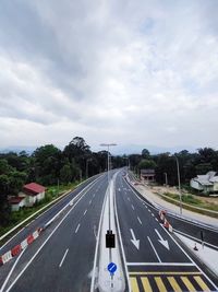 Vehicles on road against cloudy sky