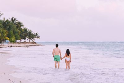 Rear view of couple standing in sea against sky