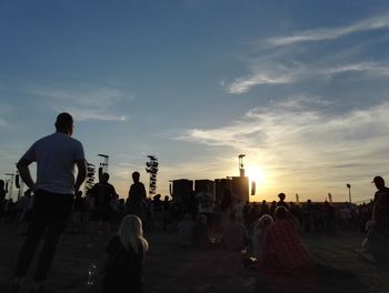 People at music concert against sky during sunset