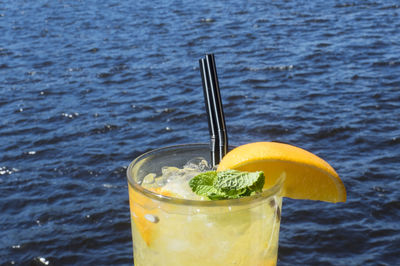 Close-up of lemonade in glasses against sea