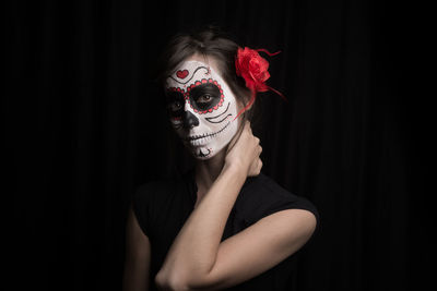 Portrait of young woman with face mask against black background