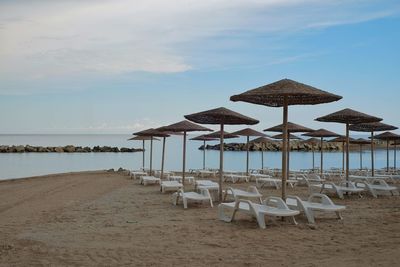 Deck chairs on beach against sky