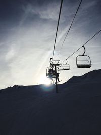 Low angle view of ski lift over snow covered mountain against sky