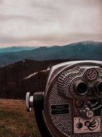 Close-up of coin-operated binoculars against landscape