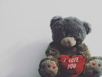 Teddy bear with red heart shape against white background