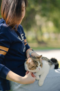 Asian woman feel happy during relax and play with her cat at park