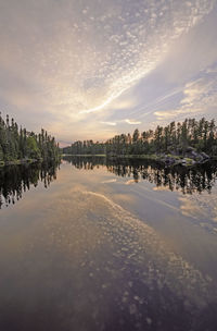 Scenic view of lake by buildings against sky during sunset