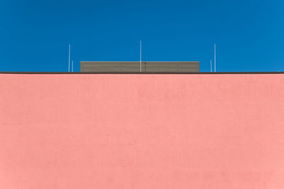 Low angle view of orange wall against blue sky