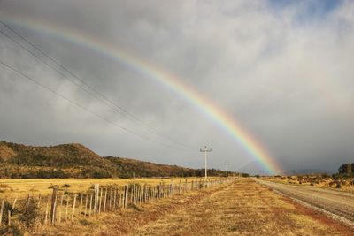 Scenic view of rainbow over field against sky