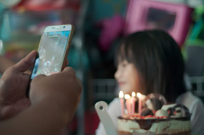 Close-up of cute girl sitting by cake at home