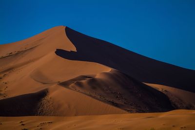 Scenic view of desert against clear blue sky