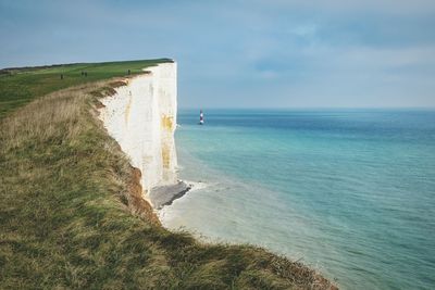 Scenic view of cliff by sea against sky