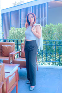 Portrait of young woman standing against railing