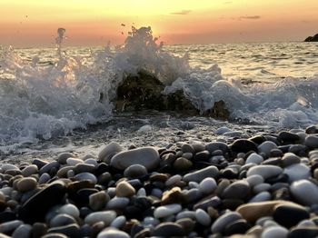 Water splashing on rocks at beach during sunset