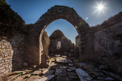 Archway in abandoned cemetery against sky on sunny day