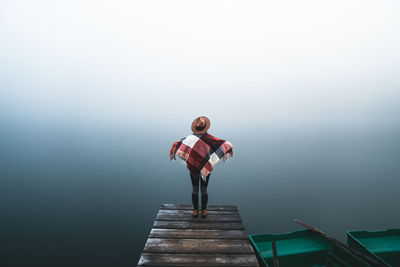 Rear view of woman walking on pier against clear sky