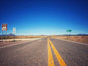 Empty road against clear blue sky