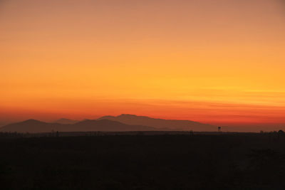 Scenic view of silhouette landscape against orange sky