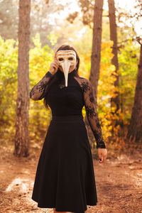 Woman standing by tree in forest