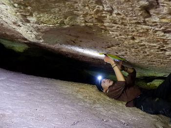 Rear view of woman on rock formation in cave