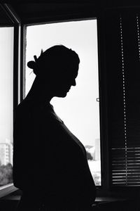 Side view of silhouette man standing by window at home