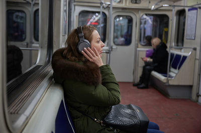 Side view of woman listening music in subway train