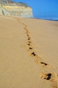 Footprints on sand at beach against sky