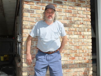 Portrait of a man standing against brick wall