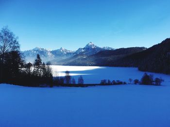 Scenic view of lake and mountains against blue sky