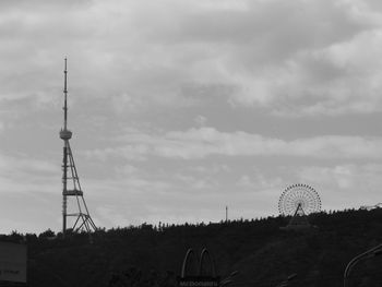 Low angle view of tower on landscape against clouds