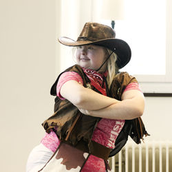 Portrait of woman in hat standing against wall