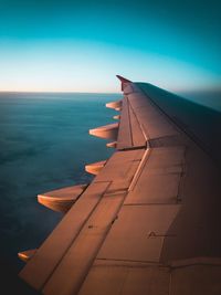 Close-up of airplane flying over sea against blue sky