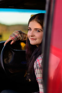 Portrait of young woman in red car