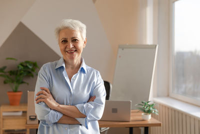 Portrait of young woman using mobile phone while sitting at home