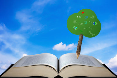 Low angle view of open book against blue sky