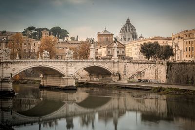 Arch bridge over river amidst buildings in city