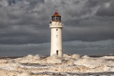 Lighthouse in sea against sky