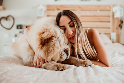 Young woman sleeping with dog on bed at home