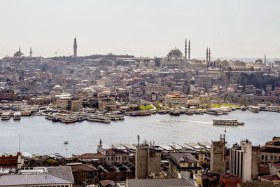 Ferries moored in sea by townscape against sky