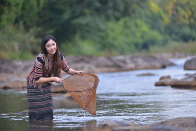 Portrait of young woman fishing in river