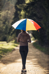 Rear view of woman standing on wet umbrella