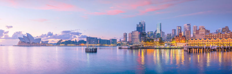 City at waterfront against cloudy sky