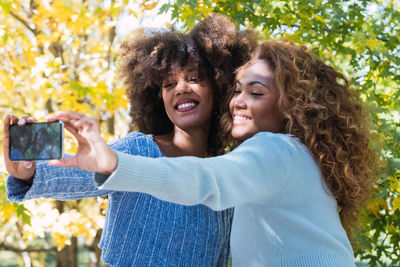 Portrait of two female afro american friends smiling while taking selfie.