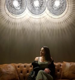 Woman sitting on sofa in illuminated room